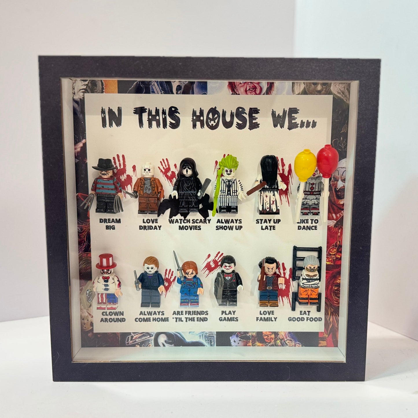 Framed artwork with LEGO figures and text 'In This House We...' on a white background