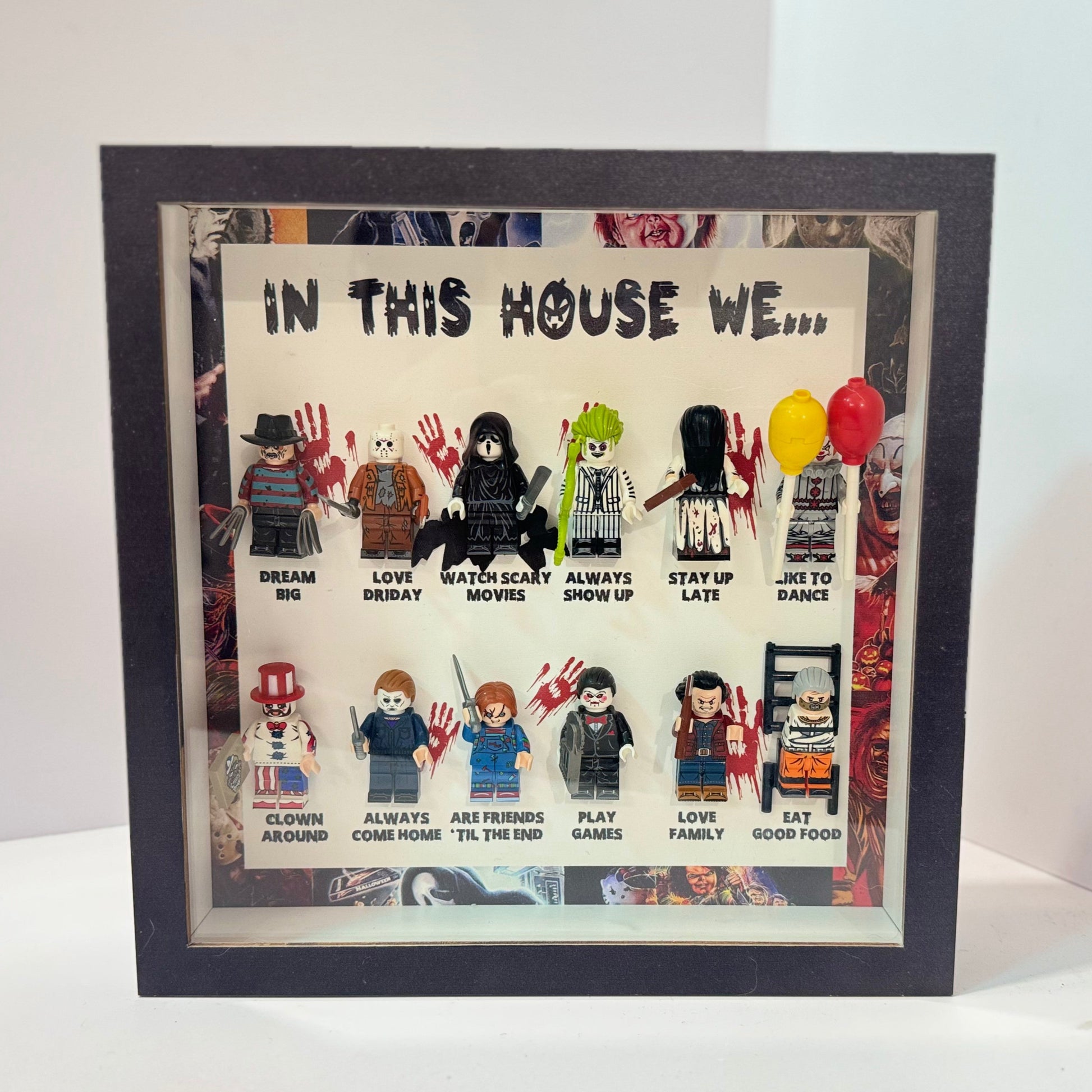 Framed artwork with LEGO figures and text 'In This House We...' on a white background