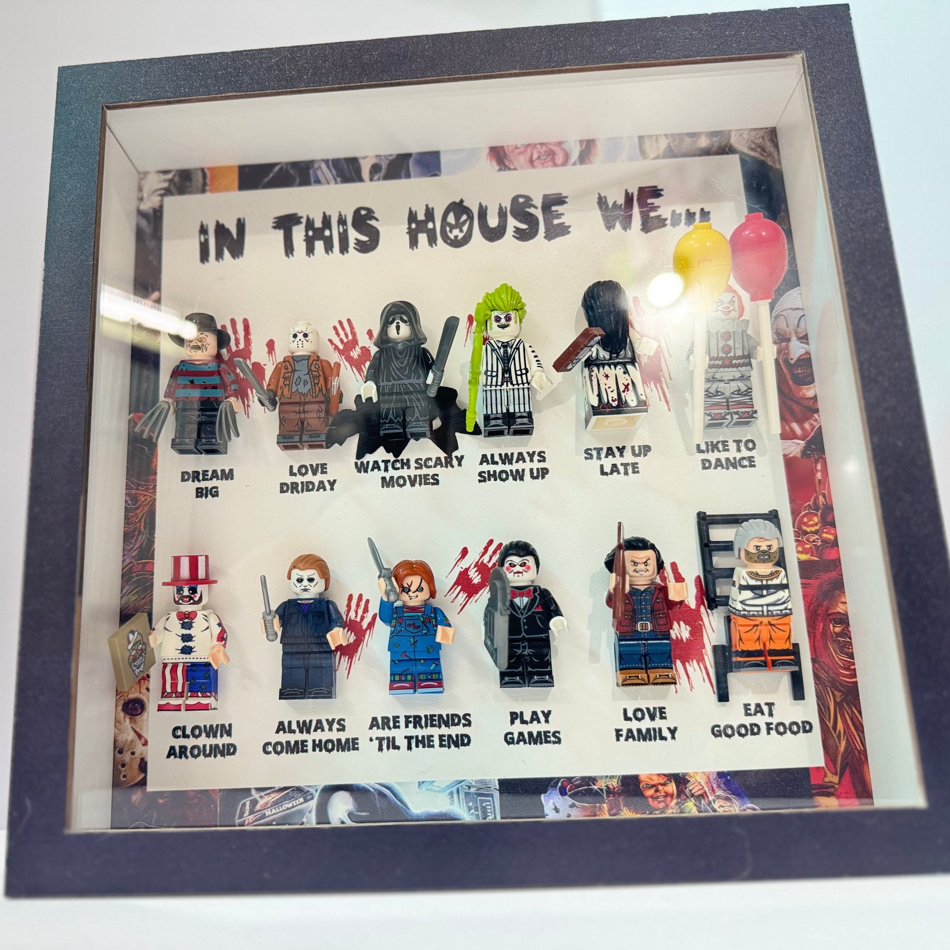 Framed artwork with LEGO figures and text 'In this house we...' on a white background.