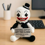 Crocheted clown toy with a sign on a desk