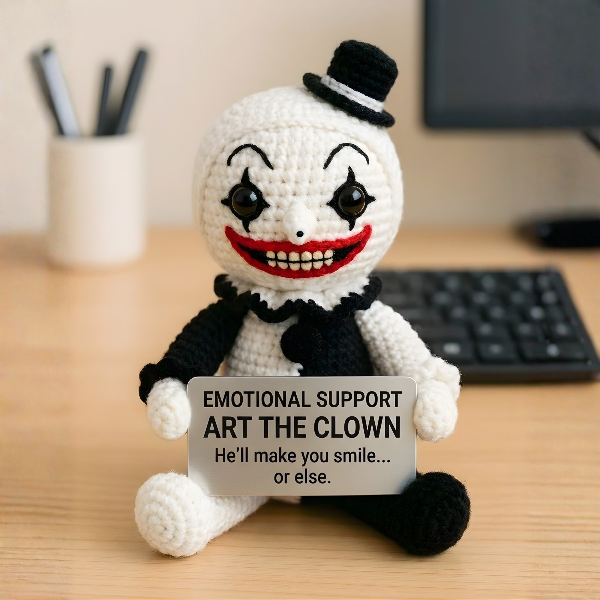Crocheted clown toy with a sign on a desk