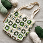 Ivory crochet green daisy granny square tote bag - handmade flat lay with yarn and crochet hook