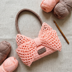 Pink crochet bow mesh shoulder bag - handmade flat lay with yarn and crochet hook
