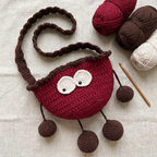 Red crochet cherry crossbody bag - handmade flat lay with yarn and crochet hook